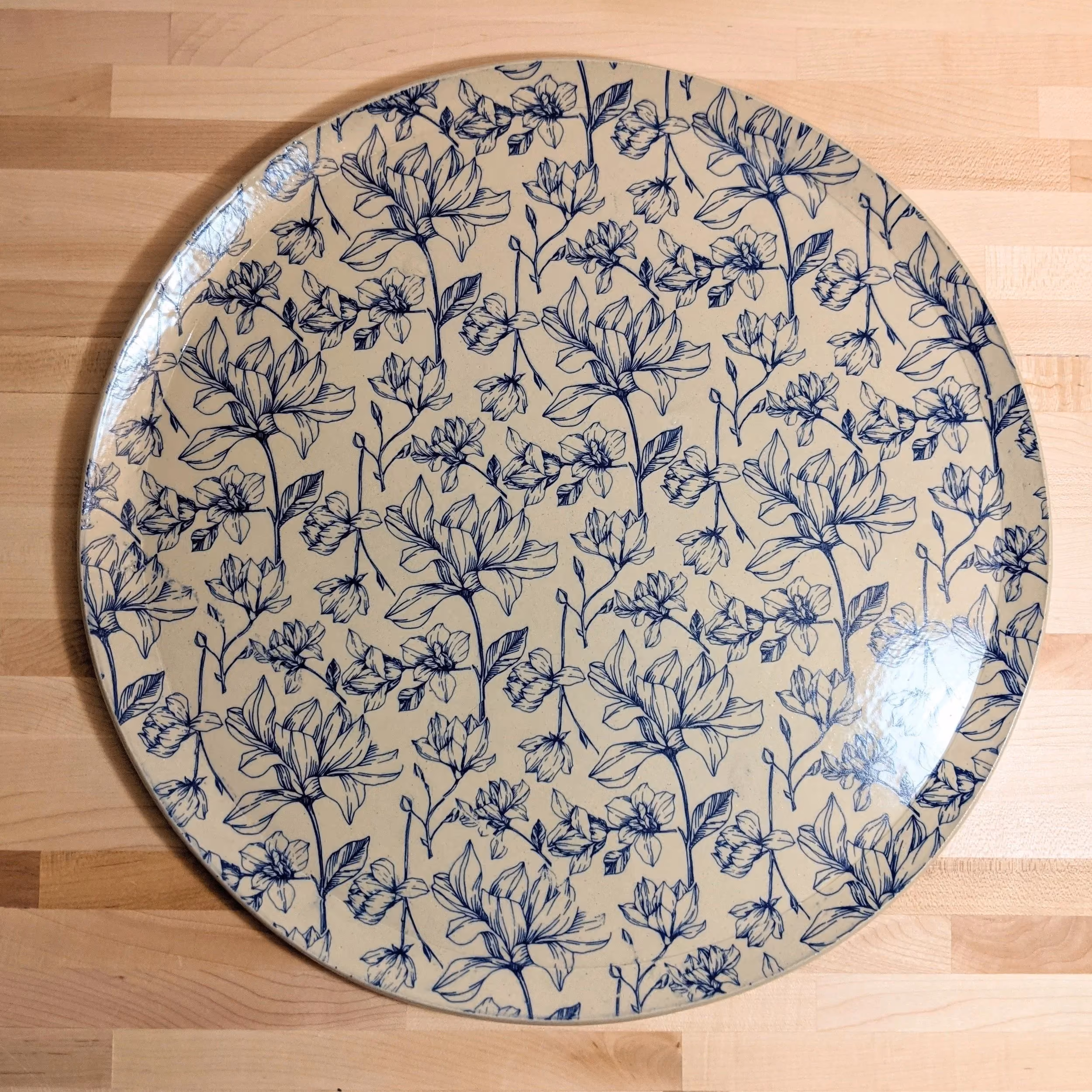 Round ceramic plate with a blue floral pattern on a light wooden surface.