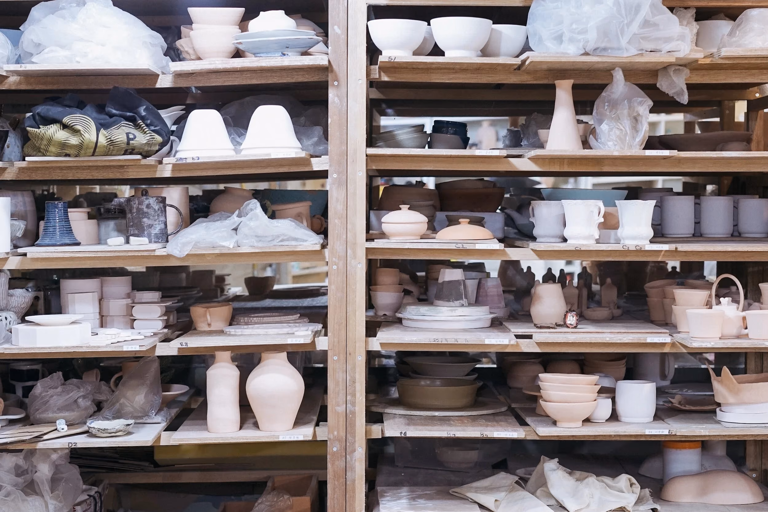 Studio shelves stacked with members' bowls, mugs and jars waiting to be fired.